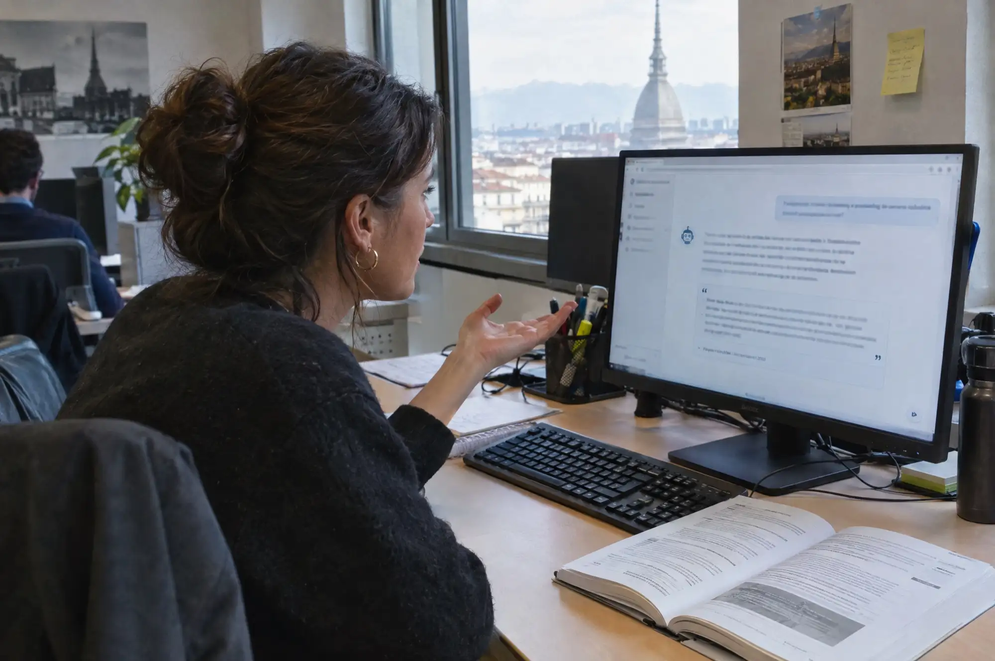 Impiegata che fa una domanda all'assistente AI con il manuale aperto accanto