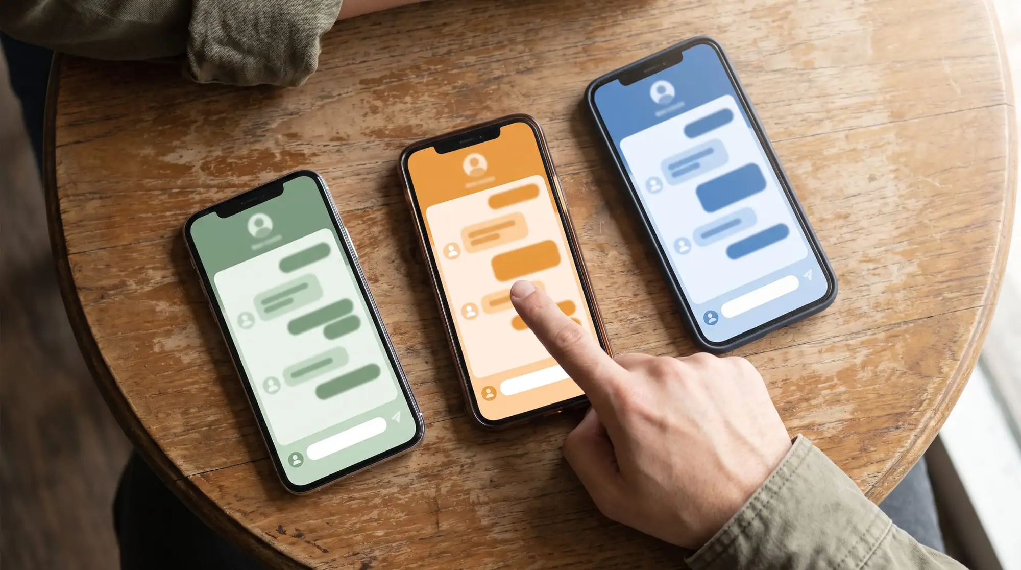 Tre smartphone con widget di chat diversi su un tavolo di legno